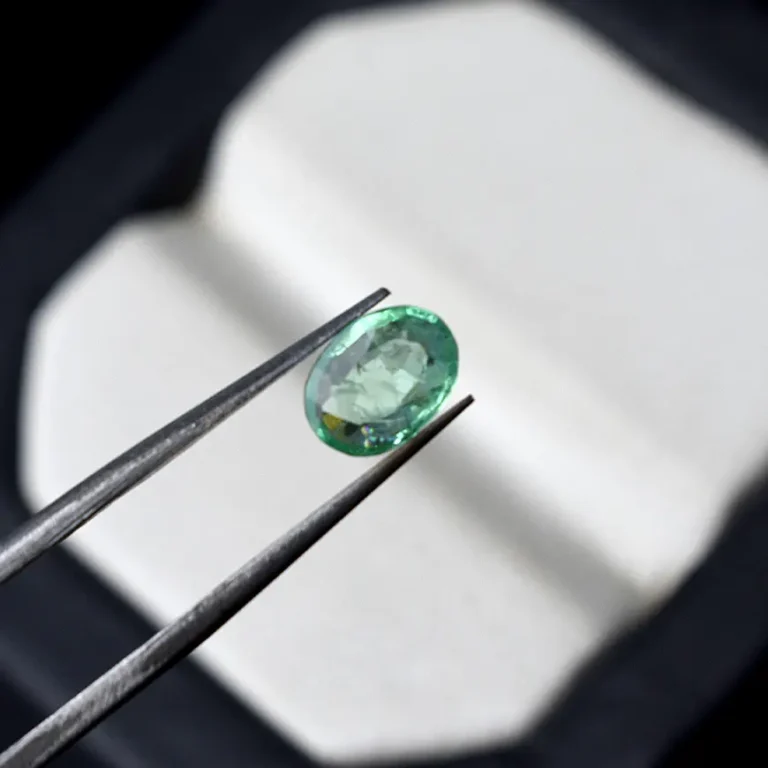 Natural emerald gemstone held with tweezers
