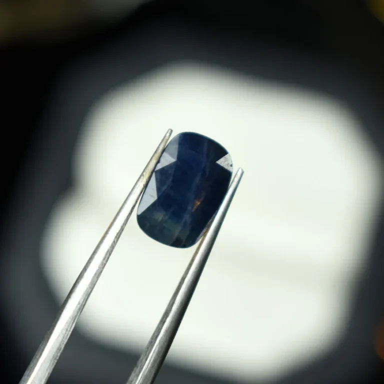 Natural blue sapphire held by tweezers