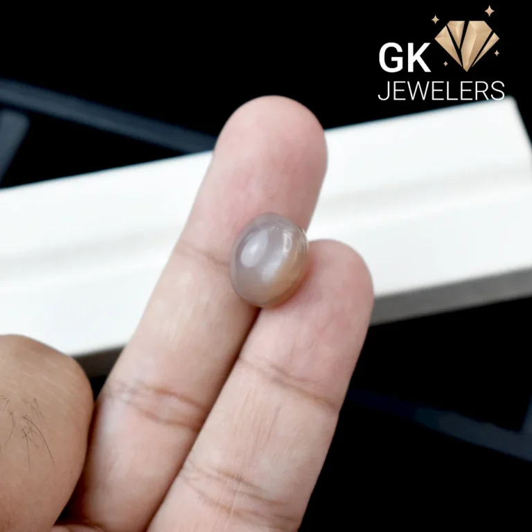 A hand holding a natural moonstone