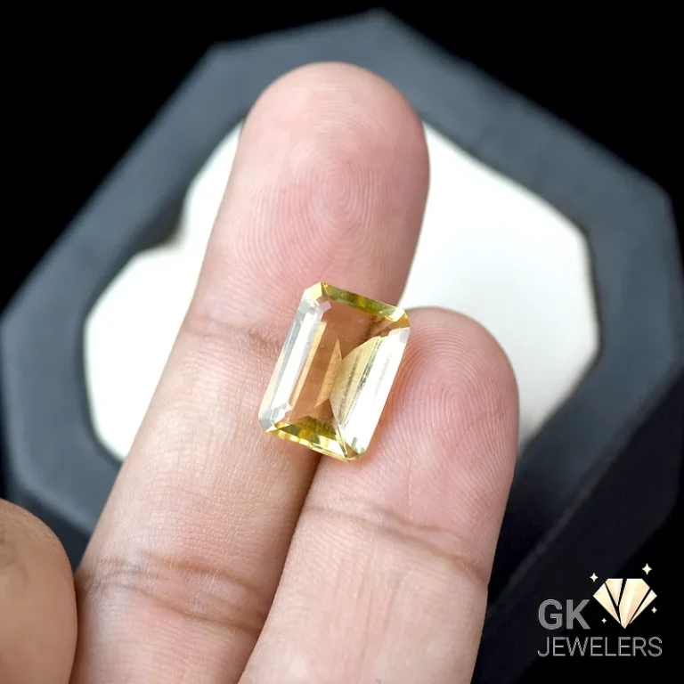 Emerald-cut citrine gemstone held between fingers