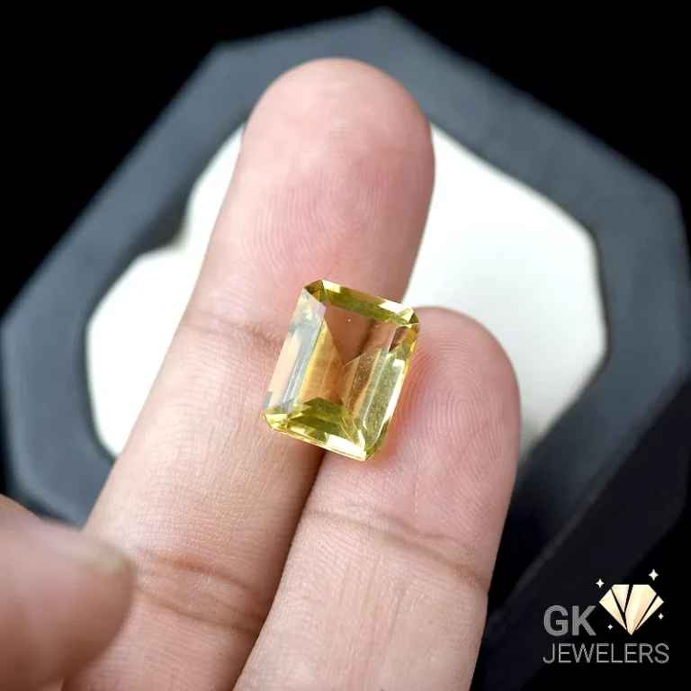 Rectangular-cut citrine gemstone held between fingers
