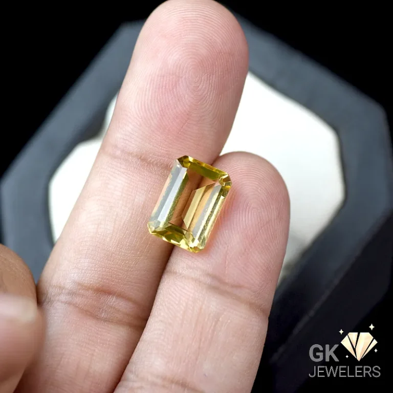 Emerald cut citrine gemstone held between fingers