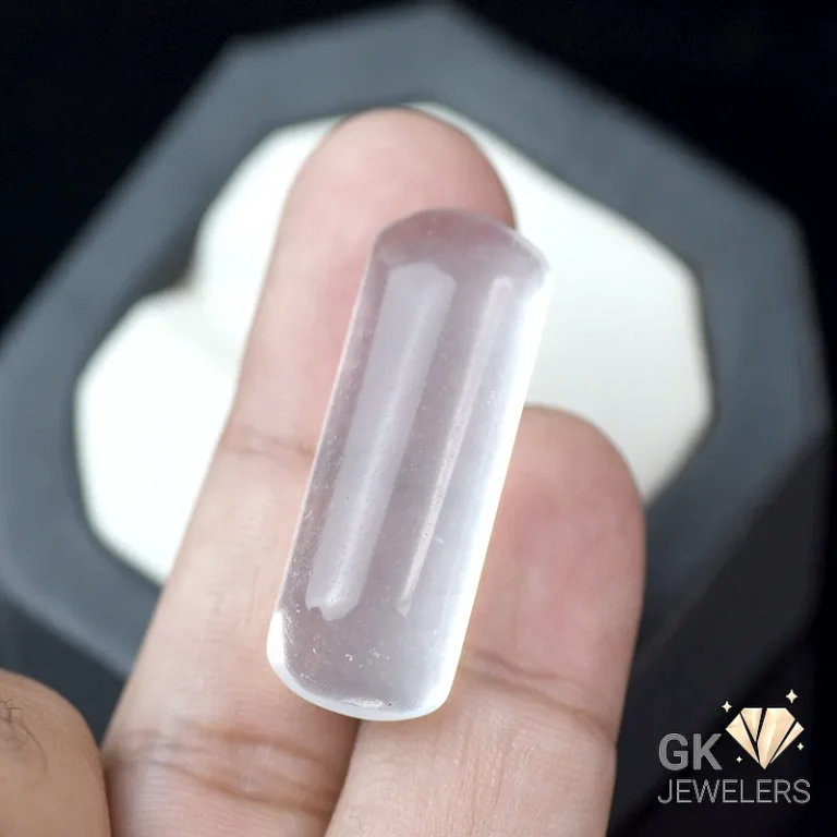 Rose quartz cabochon gemstone held between fingers