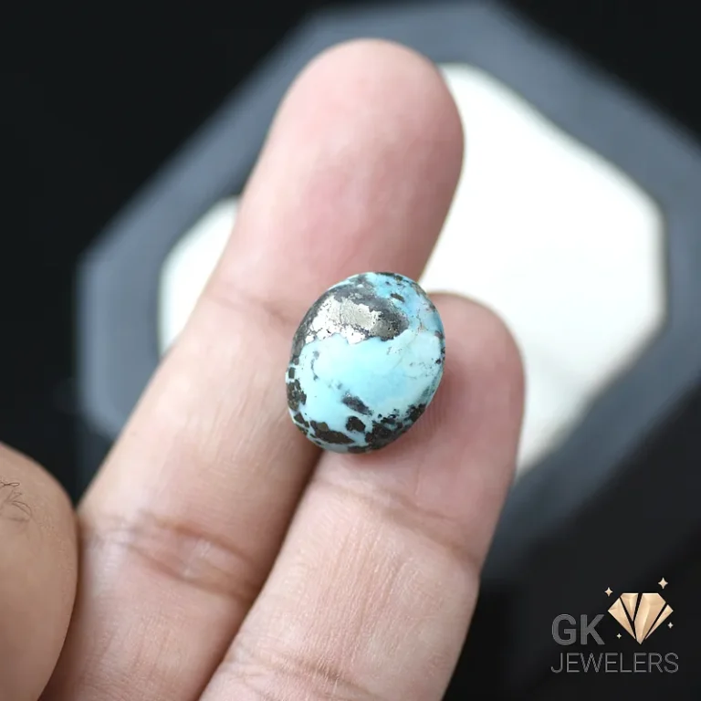 Turquoise gemstone with black matrix held between fingers