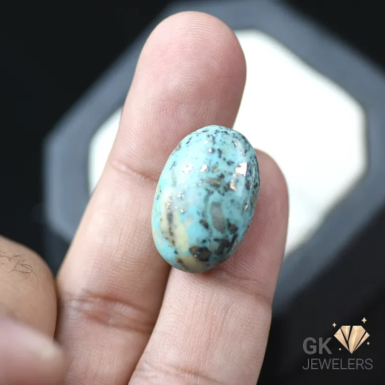 Turquoise oval cabochon with black matrix held between fingers