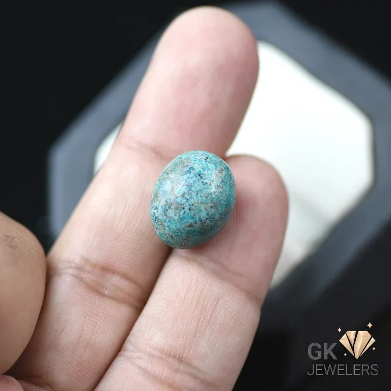 Turquoise oval gemstone with copper flecks on fingertips