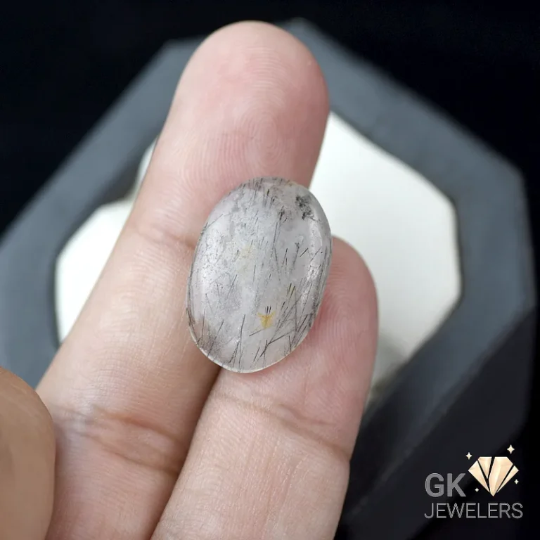 Rutile quartz gemstone held between thumb and index finger