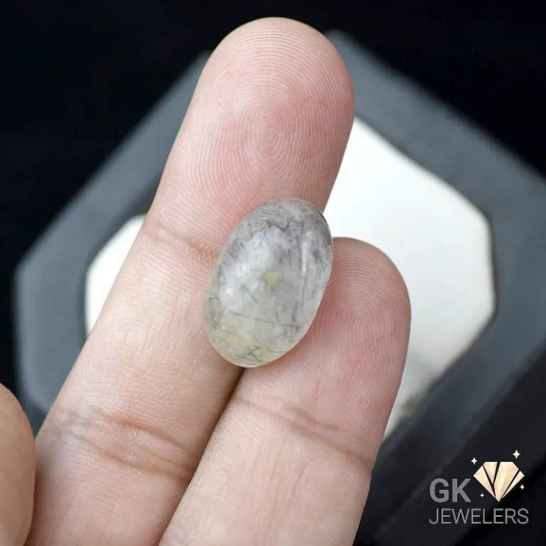 Oval grey gemstone held between fingers with subtle inclusions