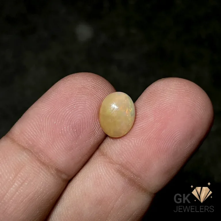 Pale yellow opal gemstone held between thumb and index finger