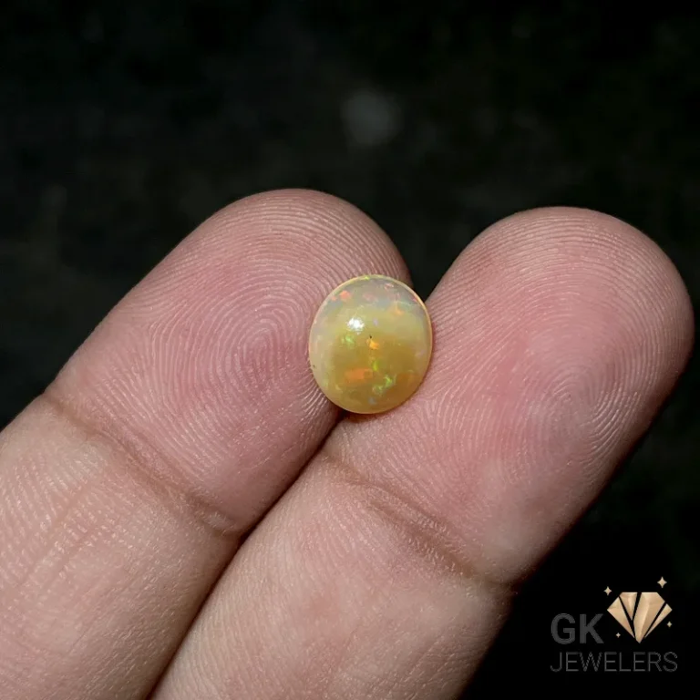 Round yellow opal gemstone held between fingers