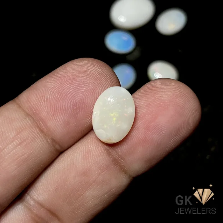 Hand holding white opal gemstone with iridescent colors