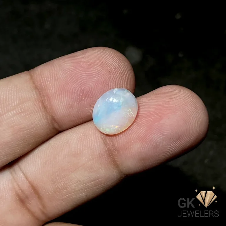 Oval opal gemstone held between fingers for scale