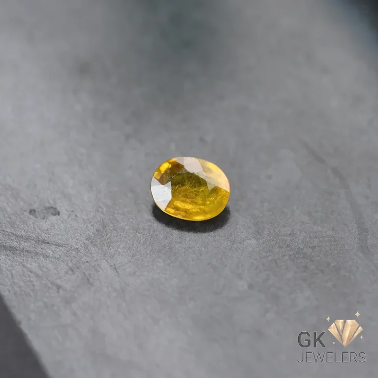 Yellow oval-cut citrine gemstone on gray slate background