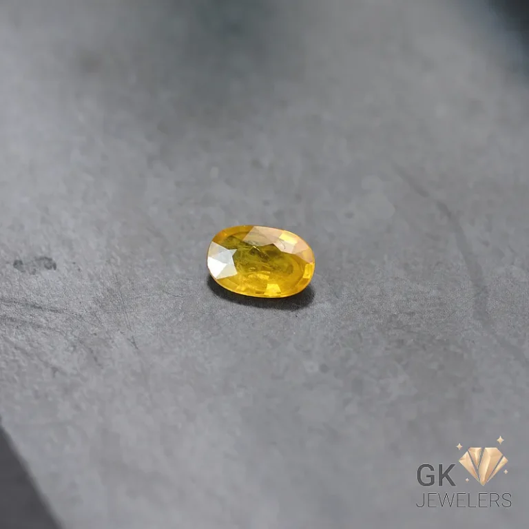 Oval-cut yellow sapphire gemstone on a gray stone surface