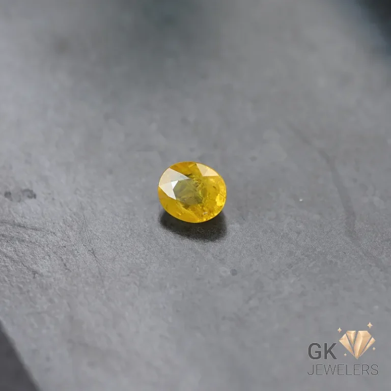 Oval yellow sapphire gemstone on a gray stone surface