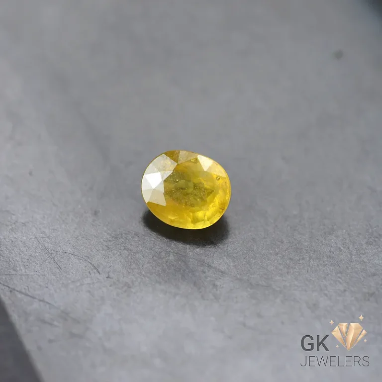 Oval-cut yellow gemstone on a gray textured surface