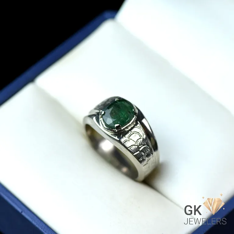 Sterling silver ring with emerald gemstone and engraved band in a blue jewelry box