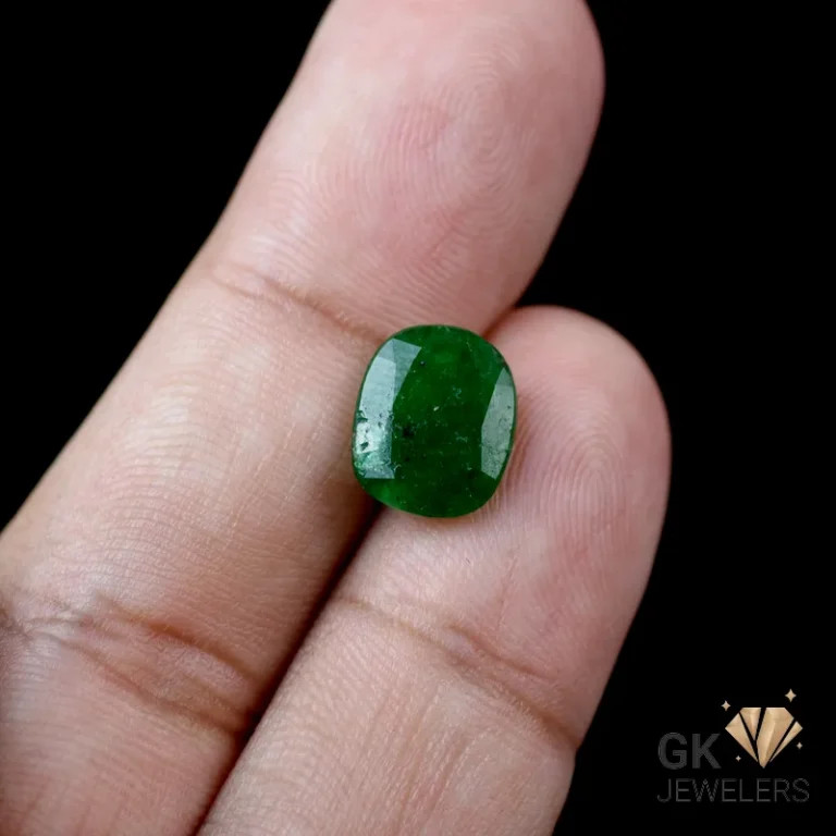 Emerald gemstone held between person's fingers