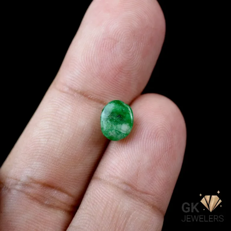 Emerald gemstone held delicately between fingers