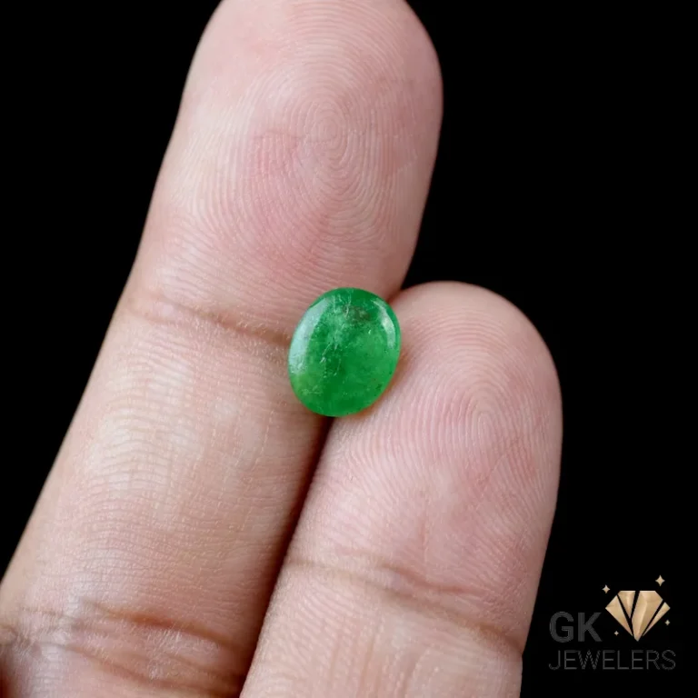 Vibrant green oval cabochon gemstone between fingers