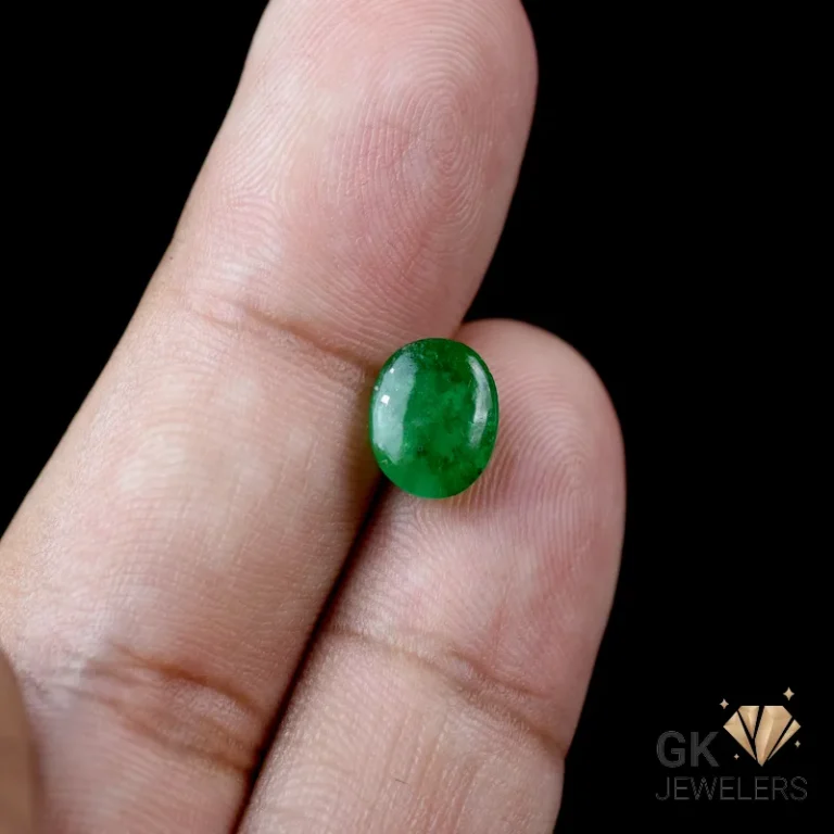 Emerald gemstone held between fingers against a black background