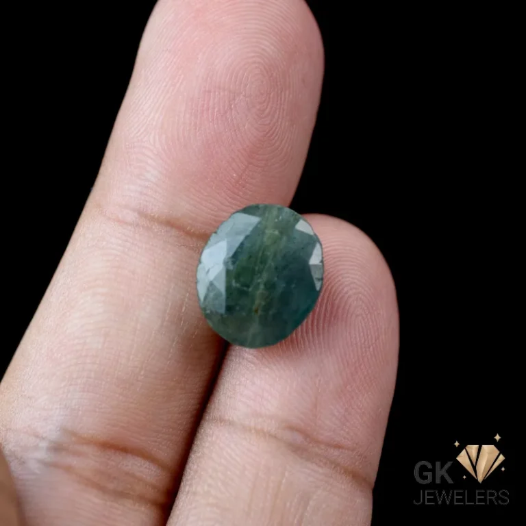 Dark green faceted gemstone on a person's fingertip