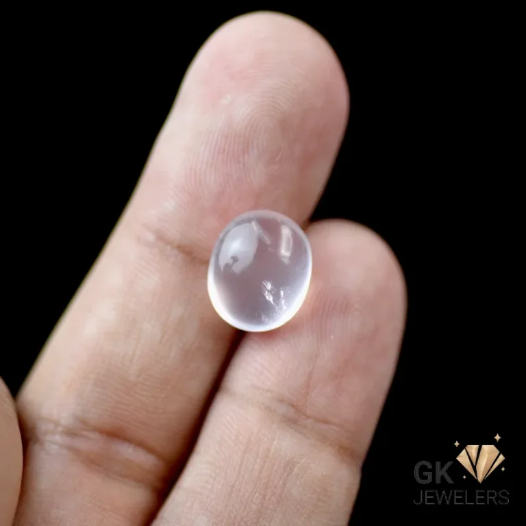 Hand holding a transparent rose quartz cabochon gemstone