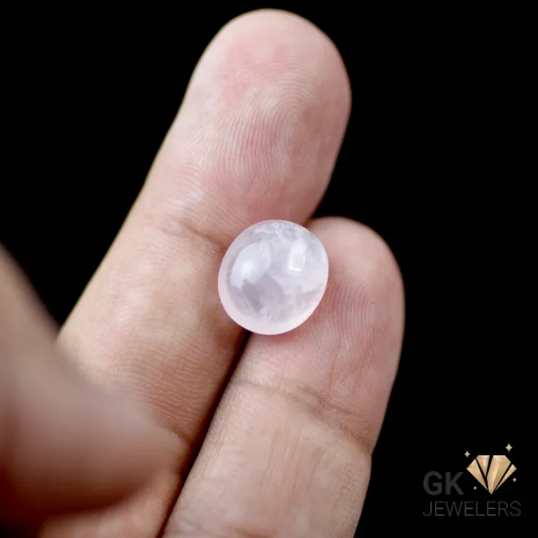Round rose quartz gemstone held between fingers