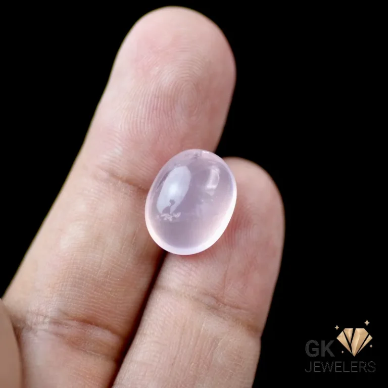 Oval rose quartz gemstone held between fingers