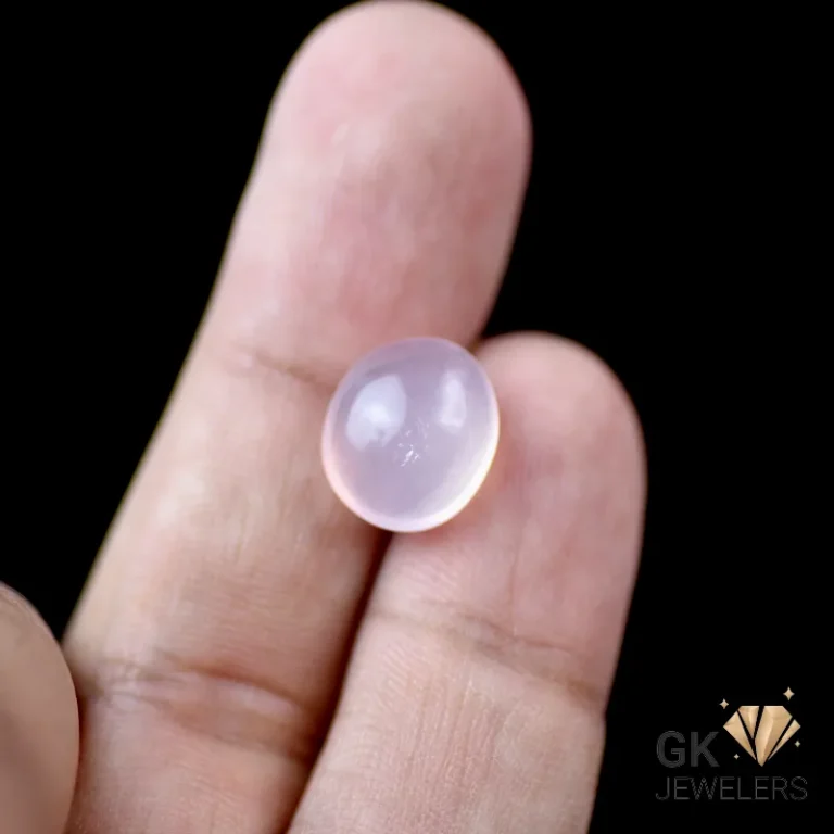 Pale pink rose quartz cabochon gemstone on human fingers