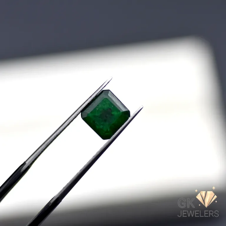 Octagonal cut emerald gemstone grasped by metal tweezers