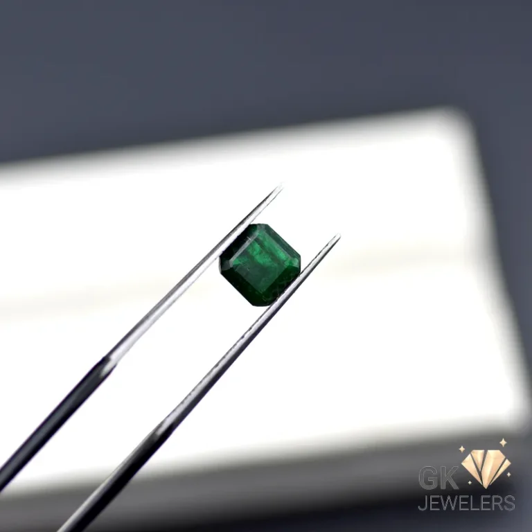 Octagonal emerald gemstone held by tweezers