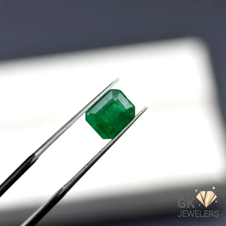 Emerald gemstone held by tweezers against a white background