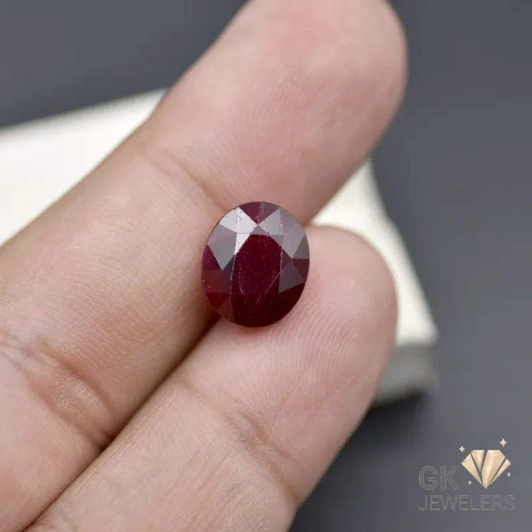 Faceted dark red garnet gemstone on a person's finger