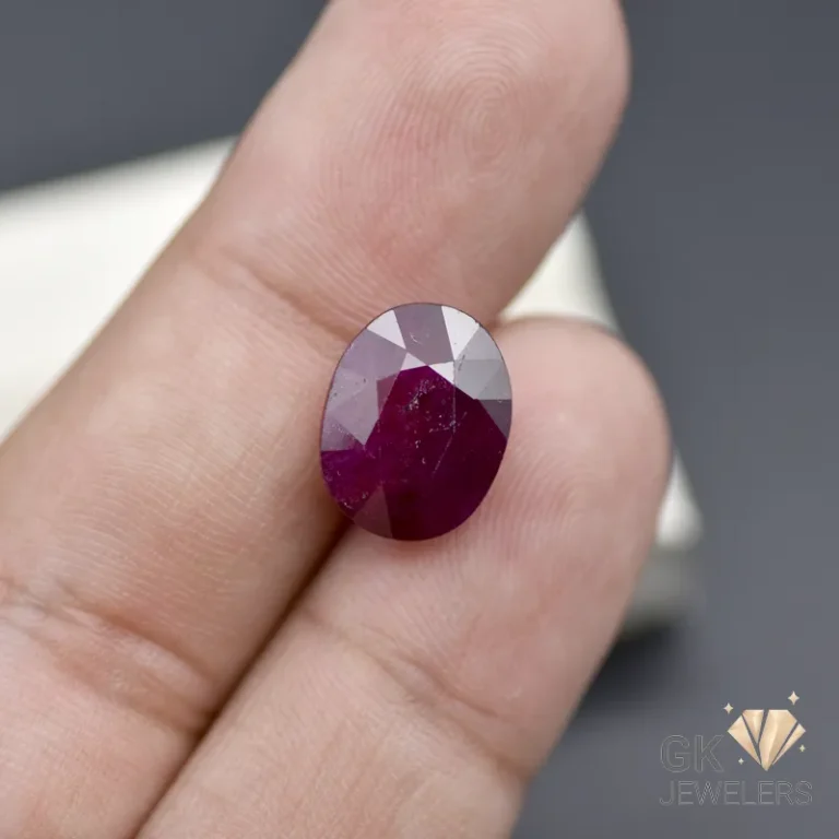 Oval-cut deep purple gemstone on a person's fingertip