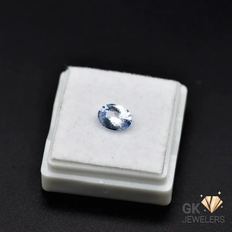 Oval cut blue sapphire gemstone on a white display stand