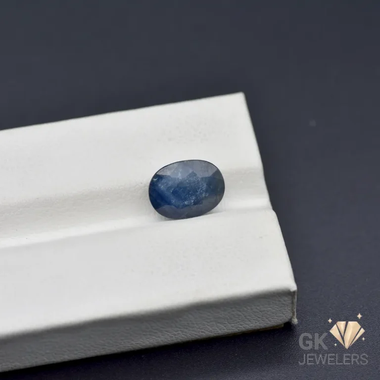 Oval-cut blue sapphire gemstone on a white jewelry box