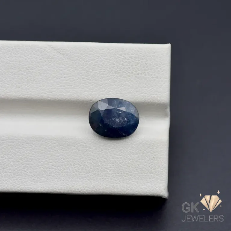 Oval cut blue sapphire gemstone on white leatherette