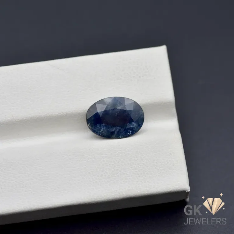 Oval-cut blue sapphire gemstone displayed on a white jewelry box