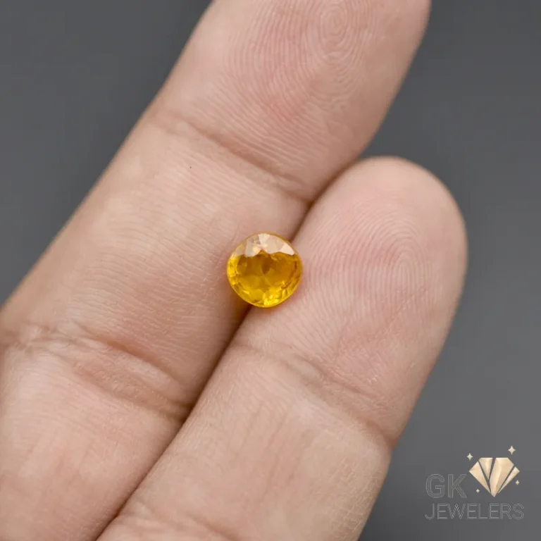 Round-cut yellow sapphire gemstone held between fingers