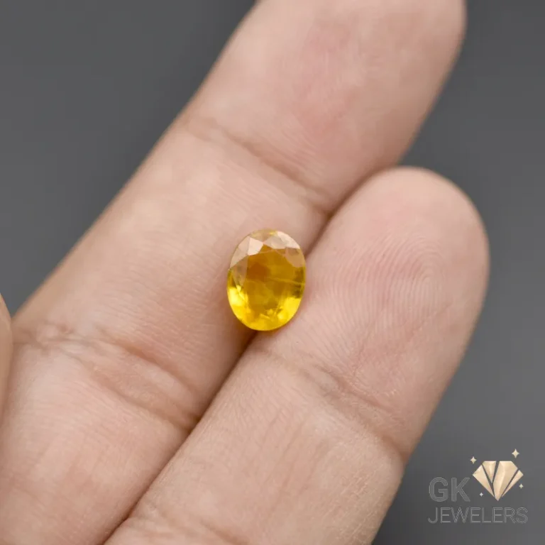 Faceted oval yellow citrine gemstone on human fingertips