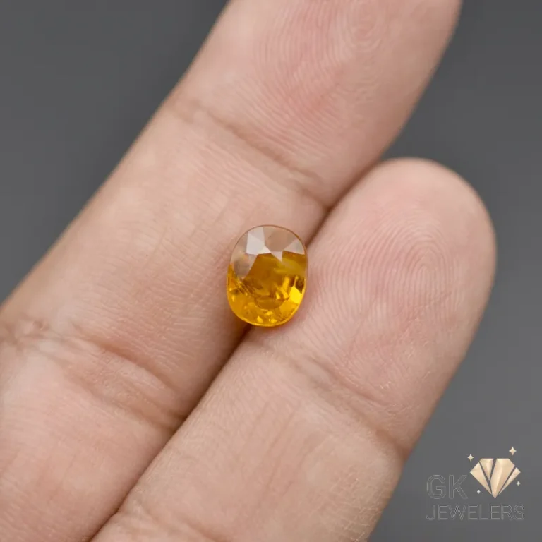 Faceted oval yellow citrine gemstone resting on a person's finger