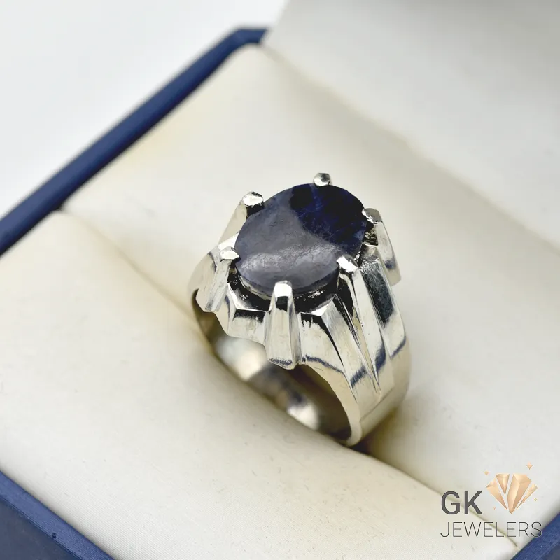 Oval-cut 6-carat blue sapphire gemstone set in a handmade silver ring, displayed in a white jewelry box with a blue border