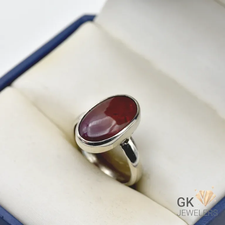 Red opal gemstone set in handmade silver ring displayed in jewelry box