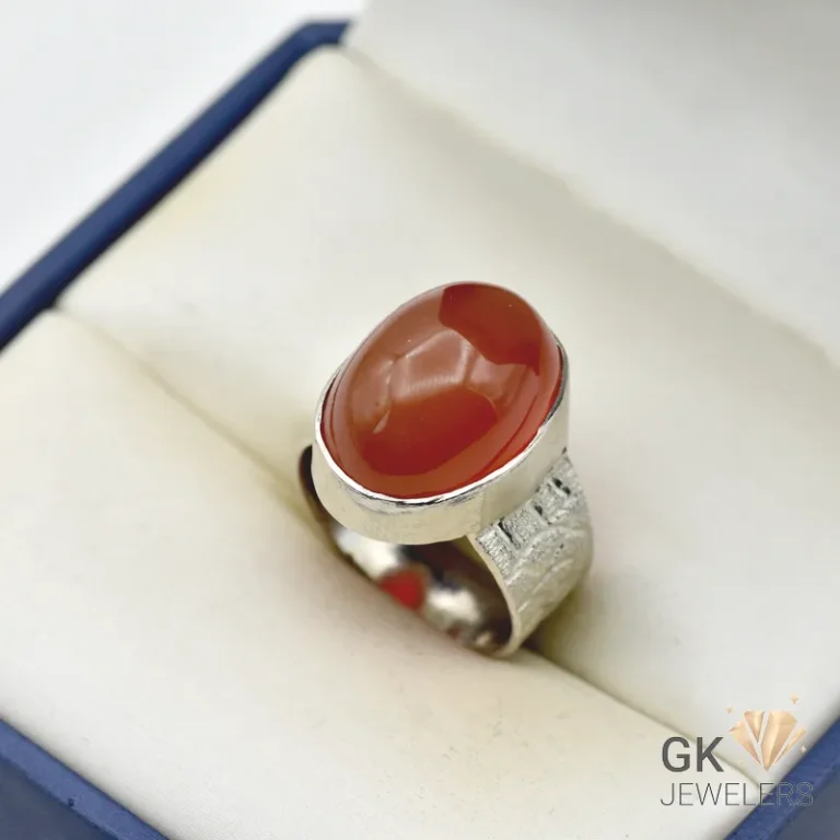 Brown agate gemstone set in a handmade silver ring, displayed in a white jewelry box with a blue border