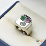Silver ring with emerald, ruby, and aquamarine gemstones totaling 2.5+ carats, set in a handmade sterling silver band, displayed in a jewelry box