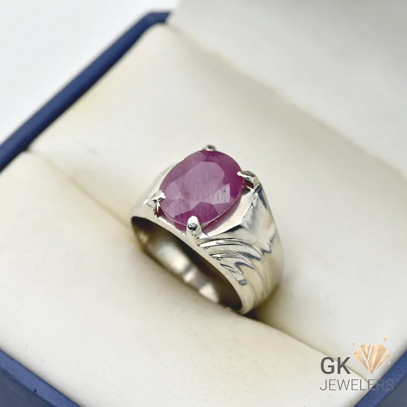Oval-cut natural ruby gemstone weighing 6 carats, set in a handmade silver ring with intricate details, displayed in a cream-colored jewelry box