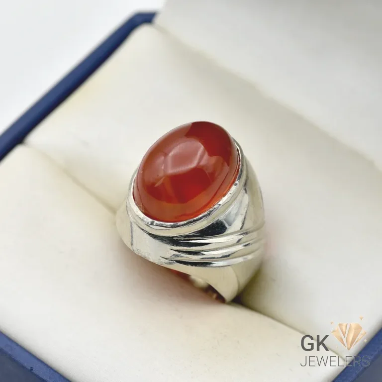 Oval-shaped red agate gemstone set in a handmade silver ring, displayed in a jewelry box with white fabric
