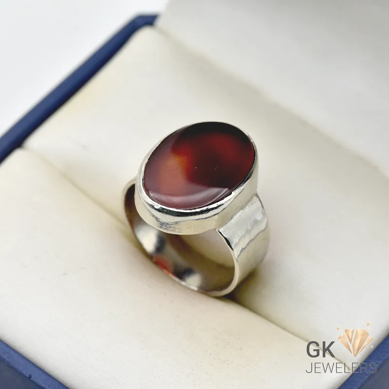 Oval dark brown agate gemstone set in a handmade silver ring, displayed in a jewelry box with white interior