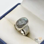 Oval Labradorite gemstone set in handmade silver ring with decorative band, displayed in a jewelry box